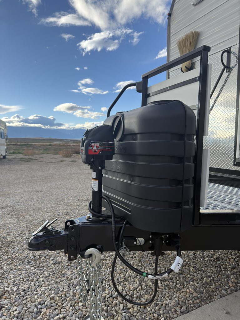 Van Niewkoop Camp #136: Trailer hitch and Bulldog electric tongue jack beside the quick-access propane tank cover.