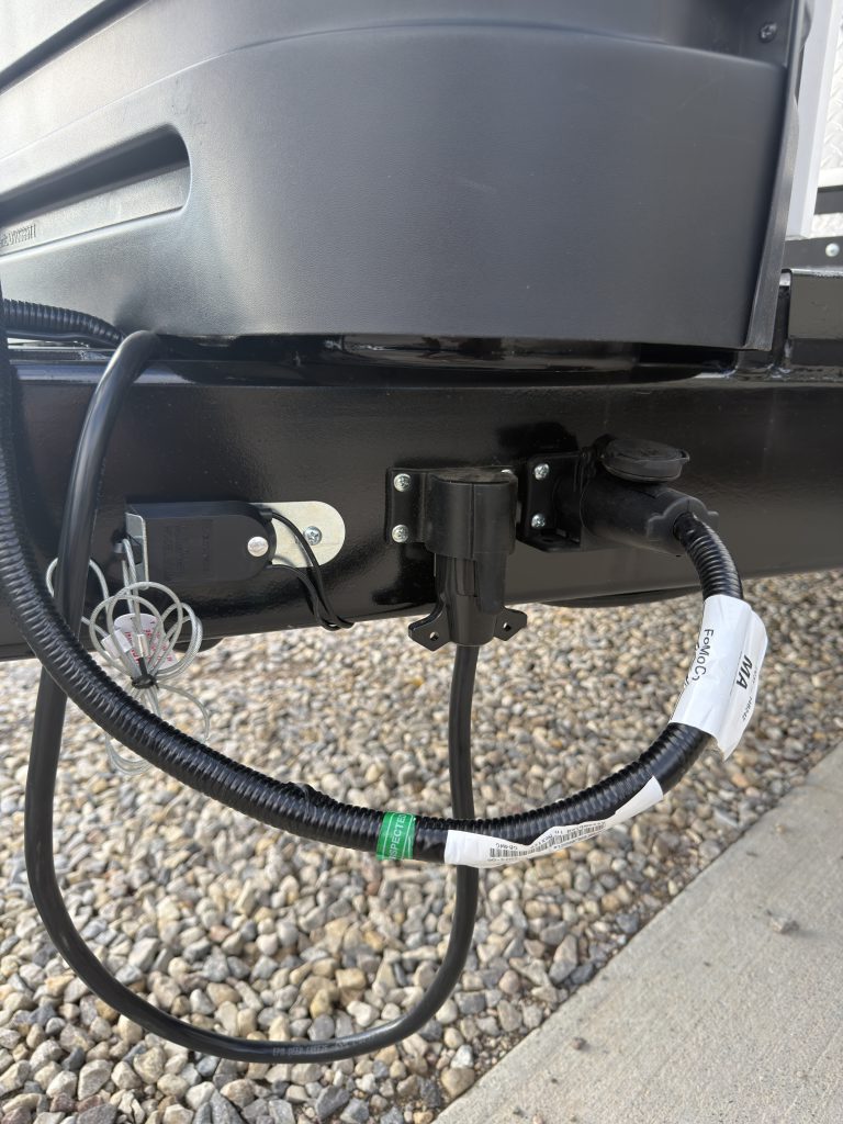 Van Niewkoop Camp #136: 7-way trailer plug connection and its mounting bracket beneath the propane tank cover.