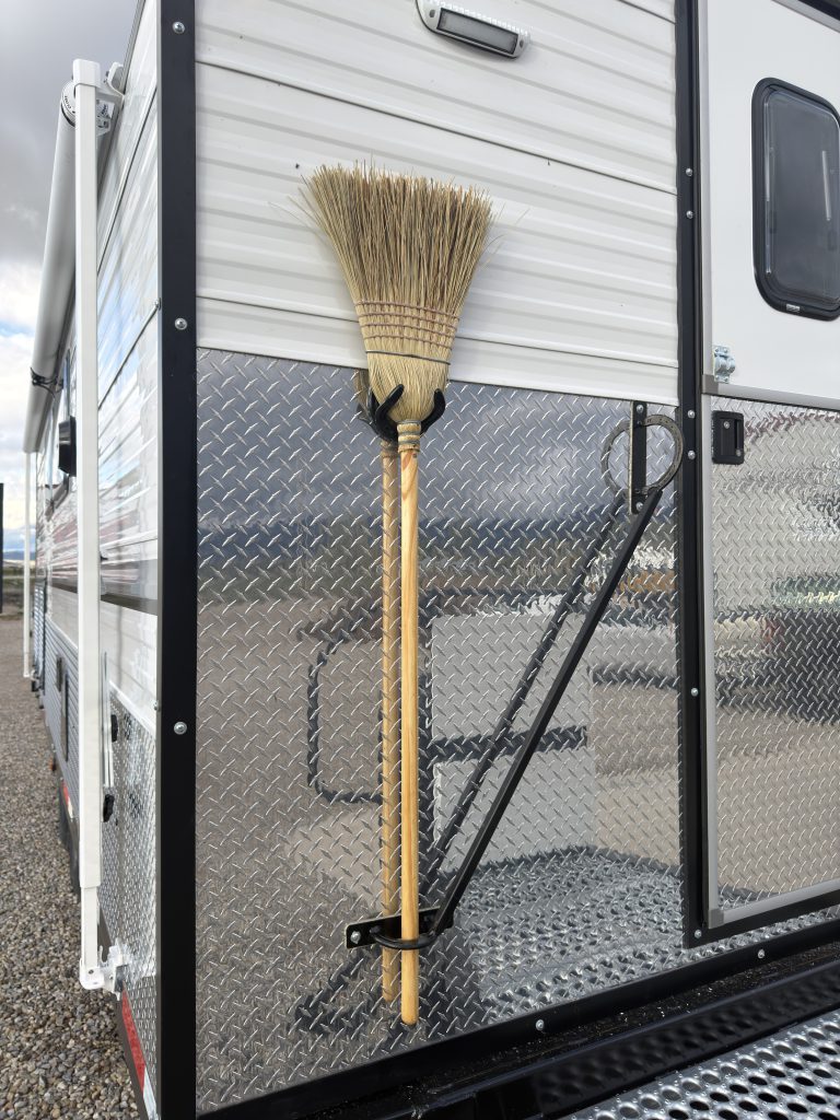 Van Niewkoop Camp #136: Corn broom secured in the horseshoe broom holder beside the front entry door.