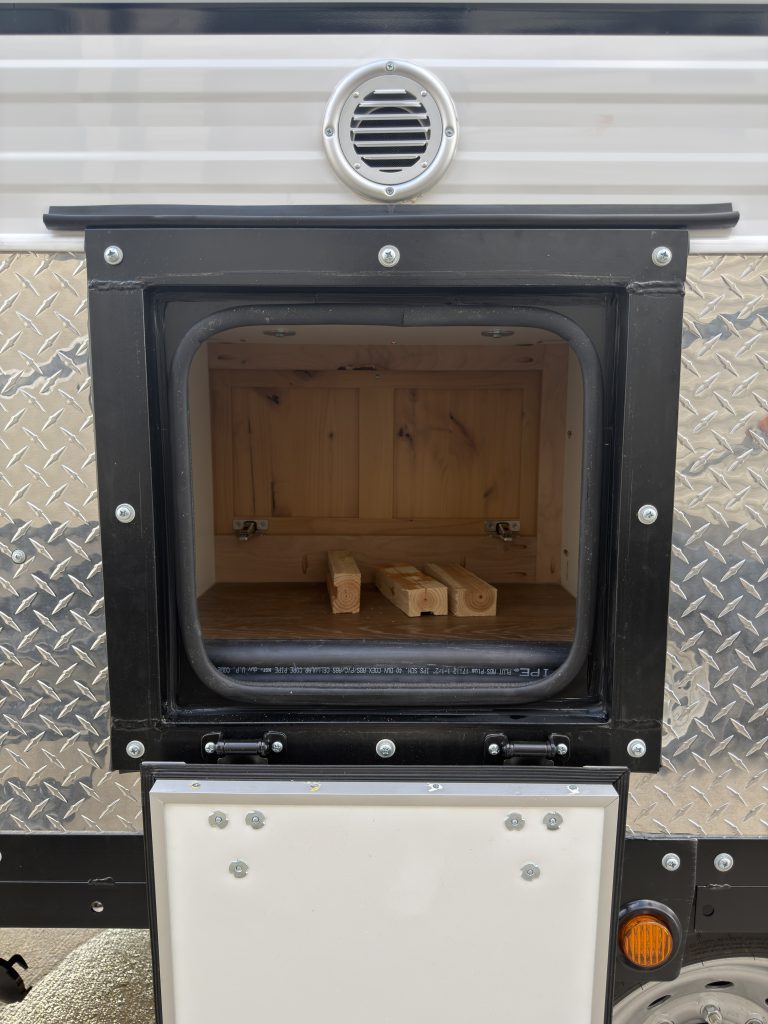 Van Niewkoop Camp #136: Open exterior access door to the pass-through wood box beneath a round air intake.