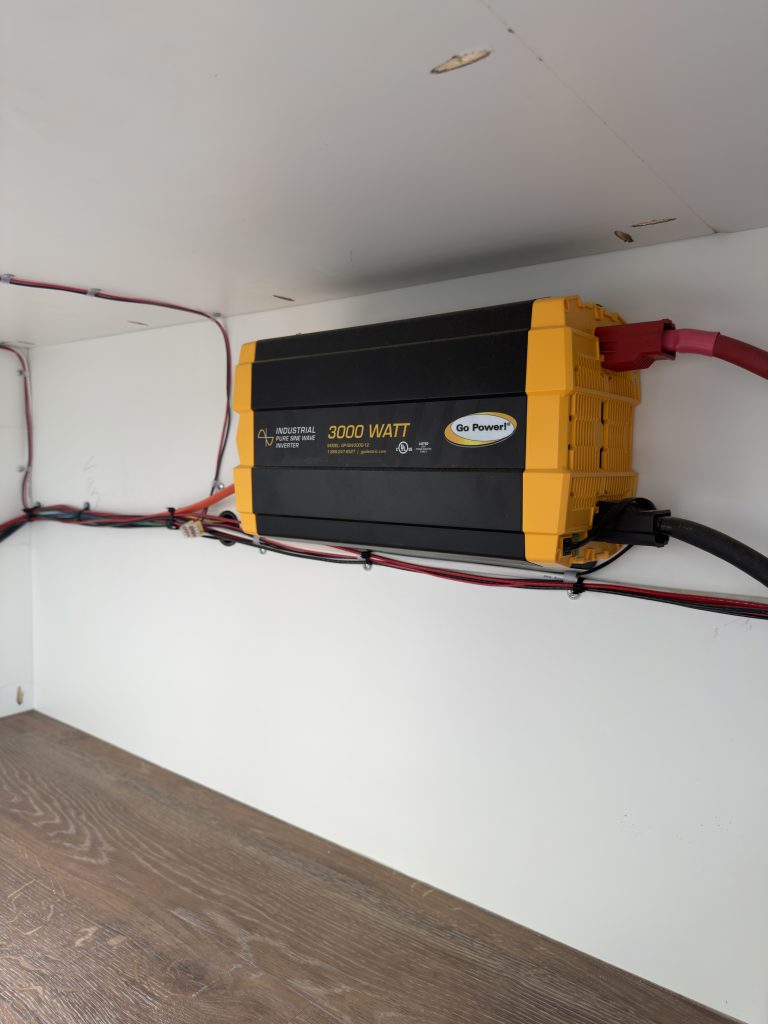 Van Niewkoop Camp #136: Wall-mounted 3,000-watt inverter with accessible power cables inside the electrical compartment.