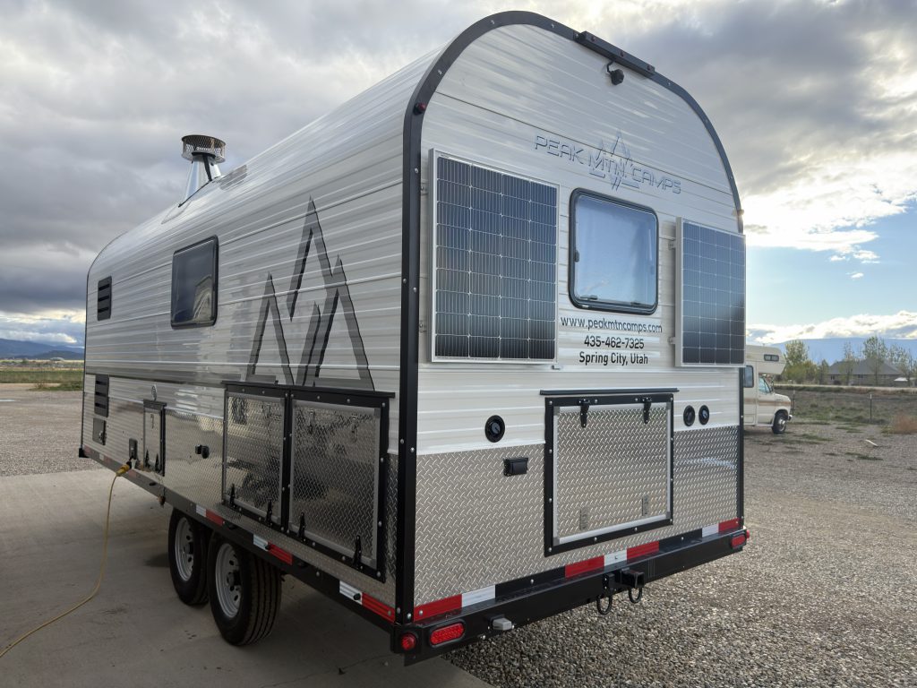 Van Niewkoop Camp #136: Rear and roadside view with solar panels, tandem axles, and exterior storage doors.