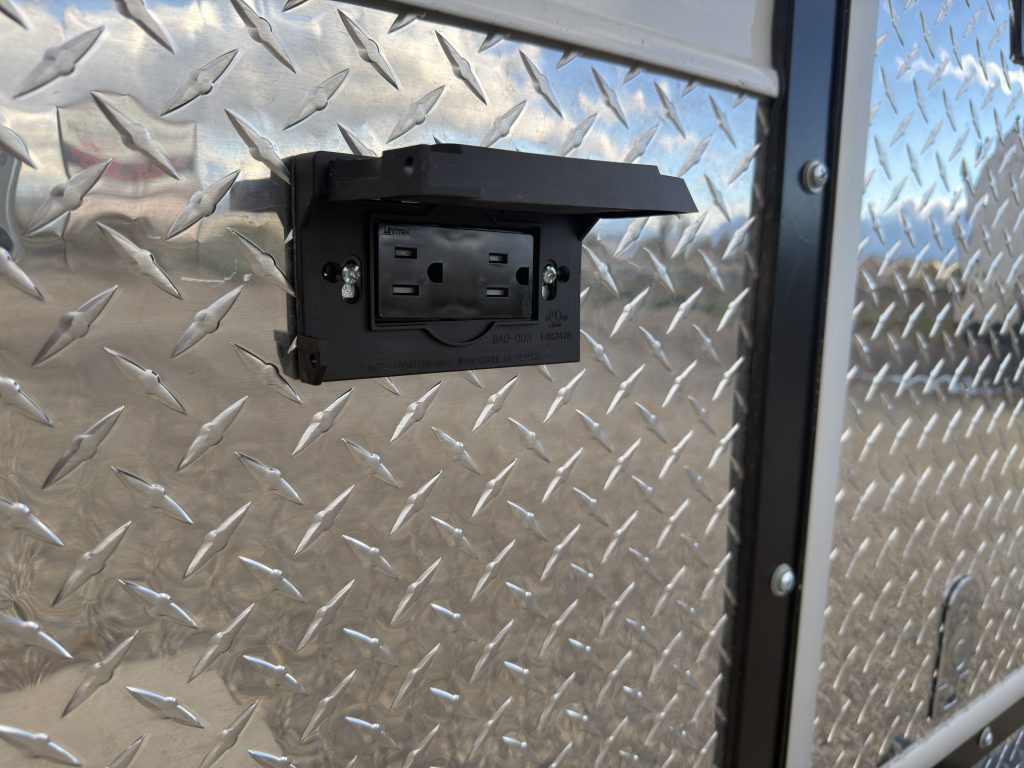 Weatherproof power outlet on the diamond-plate side wall in Van Niewkoop Camp #136.