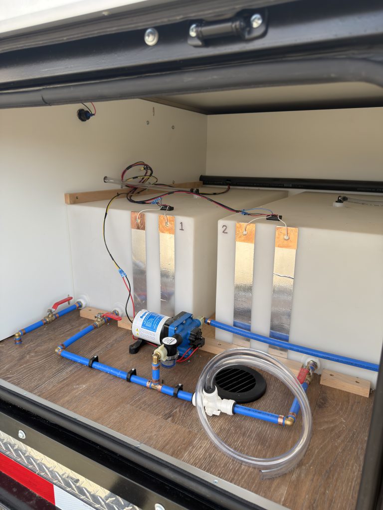 Van Niewkoop Camp #136: Water-system tubing, valves, and Shurflo pump accessible through the rear storage hatch.