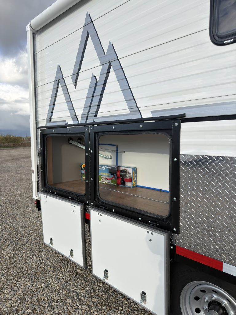 Van Niewkoop Camp #136: Raised access hatch on the tall curbside storage compartment configured for fishing rods.