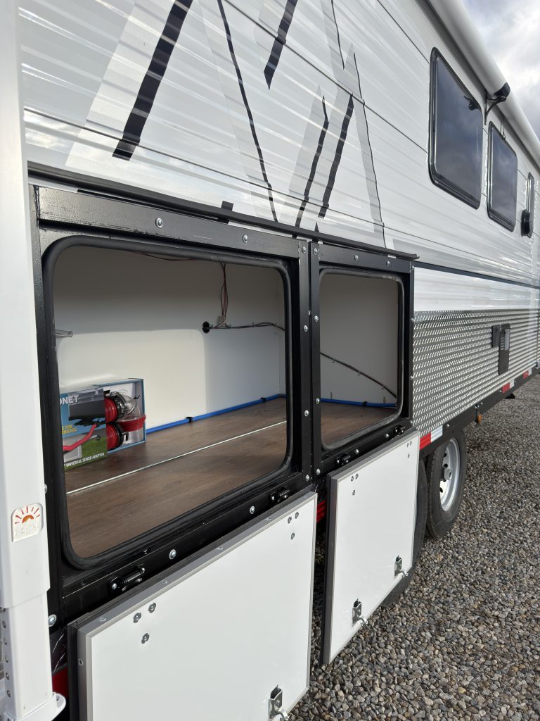Van Niewkoop Camp #136: Open curbside storage compartment with the upper hatch raised and its interior visible.