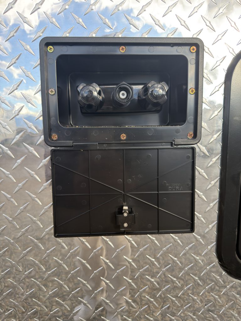 Van Niewkoop Camp #136: Exterior shower connections above the lower access cover on the diamond-plate side wall.