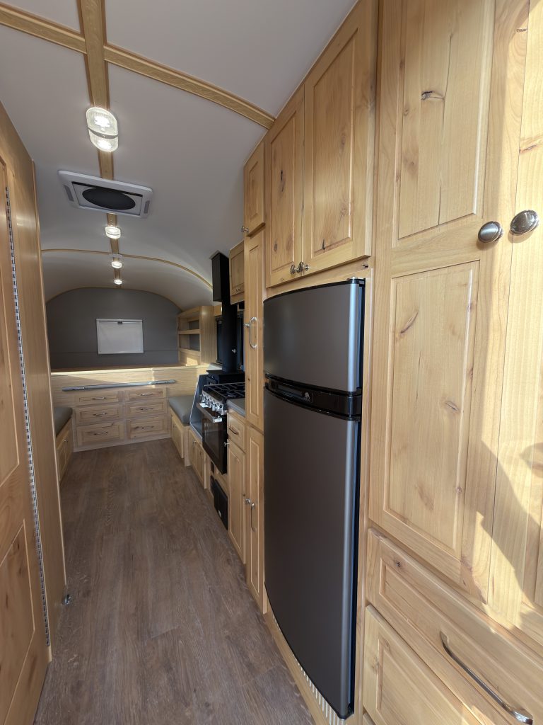 Van Niewkoop Camp #136: Interior aisle beside the Norcold fridge-freezer and tall hardwood cabinetry.