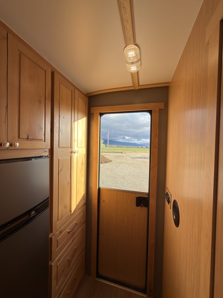 Van Niewkoop Camp #136: View toward the Dutch entry door beside the Norcold refrigerator and wood cabinetry.