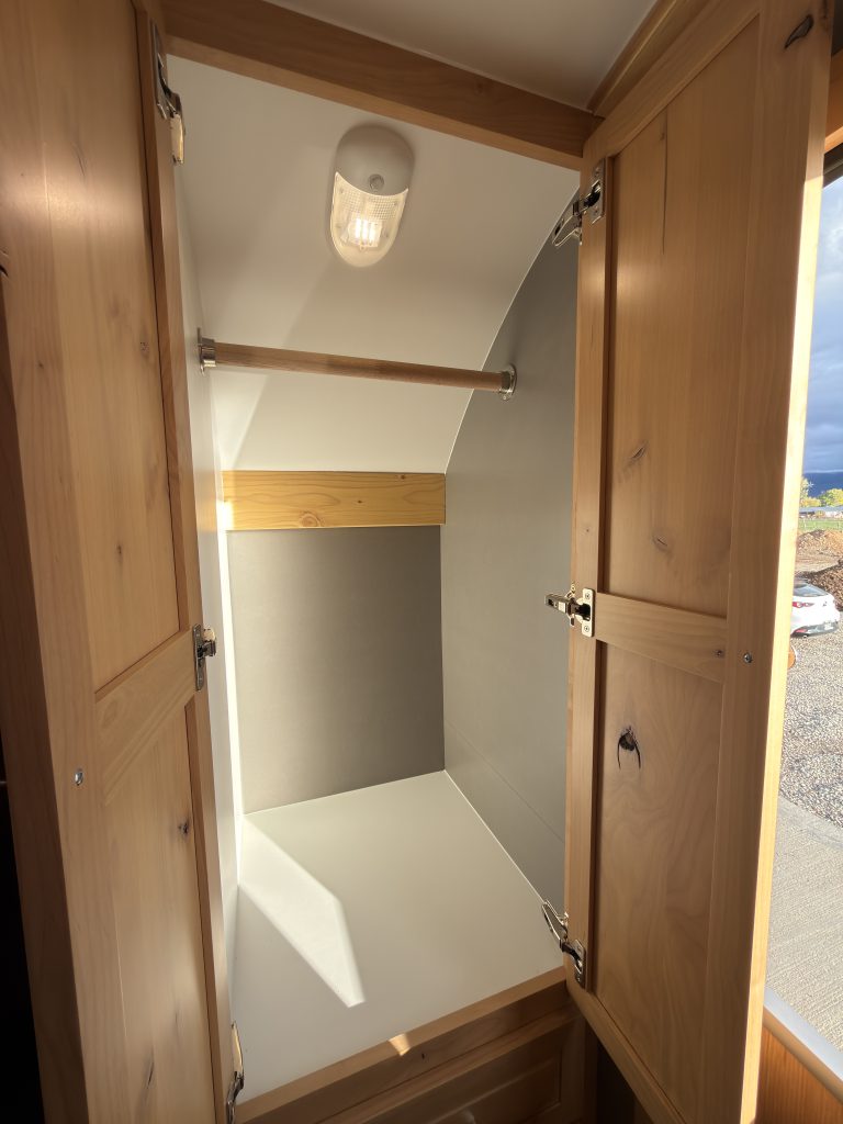 Van Niewkoop Camp #136: Open entry closet with a hanging rod and interior lighting.