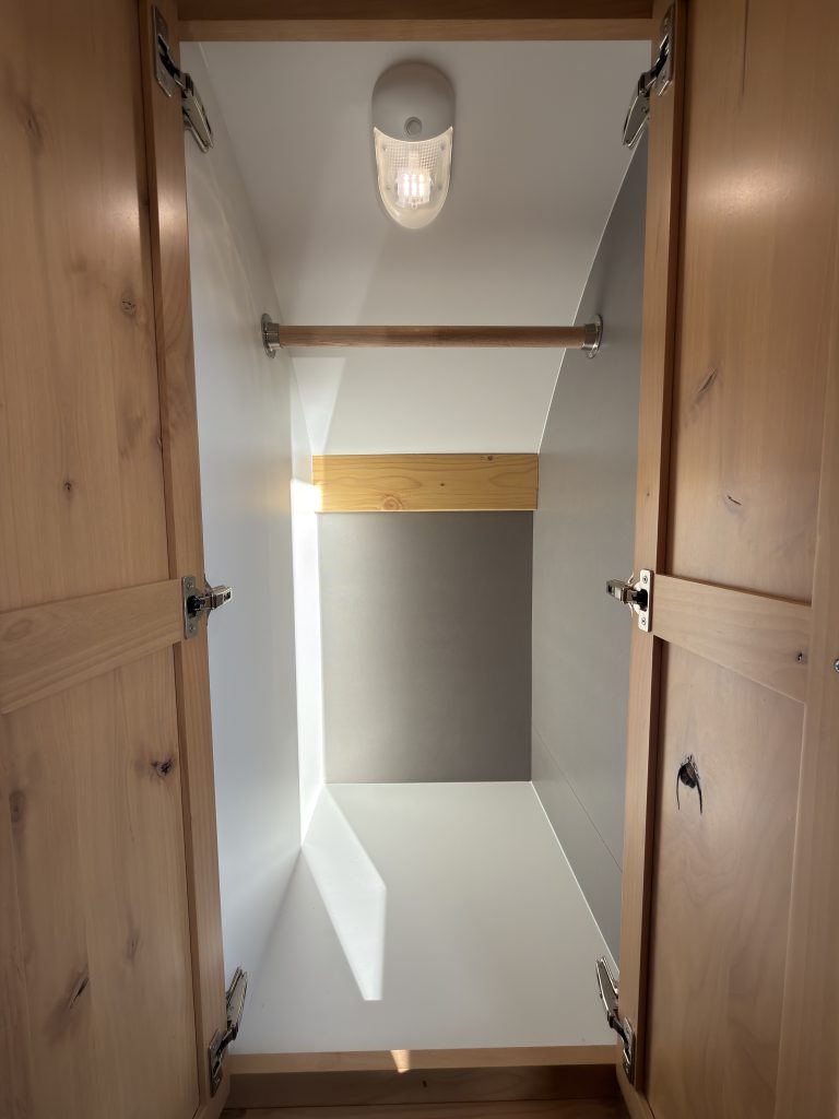 Van Niewkoop Camp #136: Inside view of the entry closet with its hanging rod and wood trim.