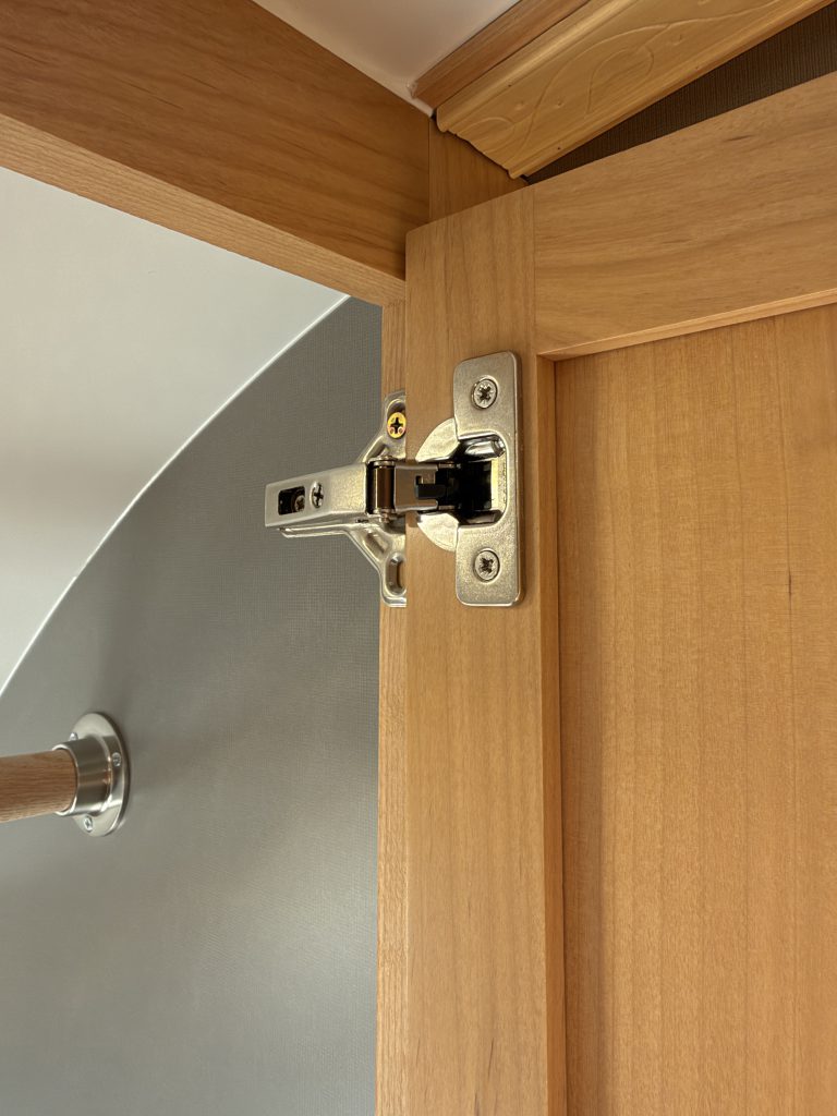 Van Niewkoop Camp #136: Close view of a soft-close hinge inside the hardwood cabinet.