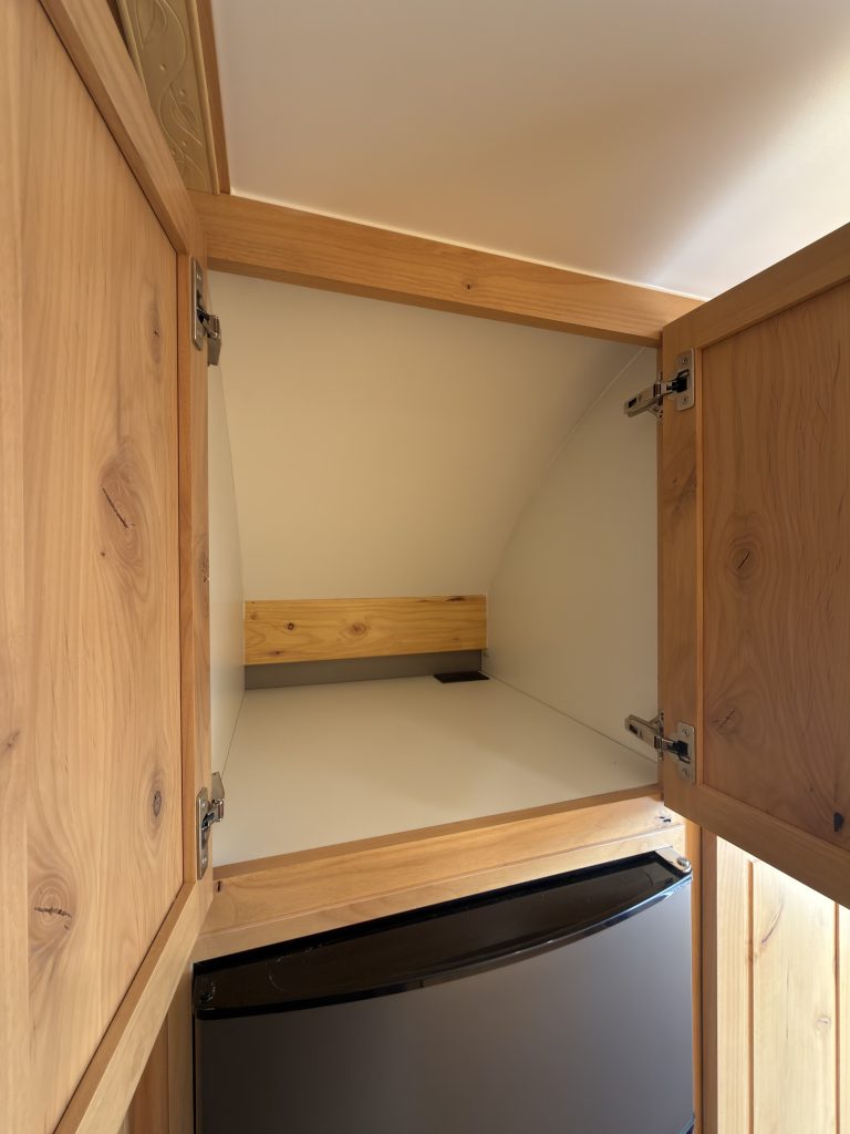 Van Niewkoop Camp #136: Open upper microwave cabinet above the refrigerator, with no microwave installed.