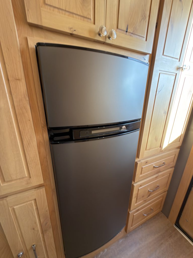 Van Niewkoop Camp #136: Closed 5.3-cubic-foot Norcold 3-way fridge-freezer set into the hardwood cabinetry.