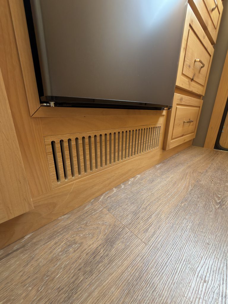 Van Niewkoop Camp #136: Wood ventilation grille for the forced-air furnace beneath the refrigerator.