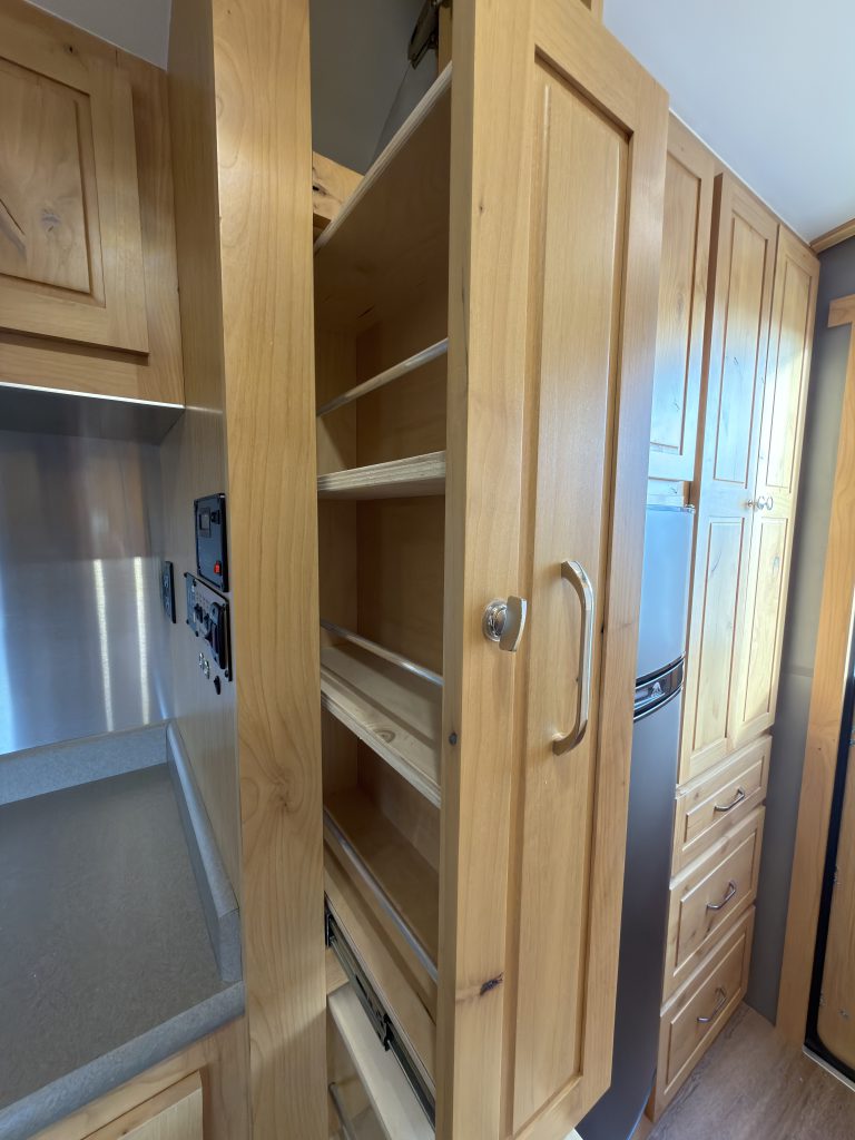 Van Niewkoop Camp #136: Open shelves in the pull-out pantry beside the refrigerator.