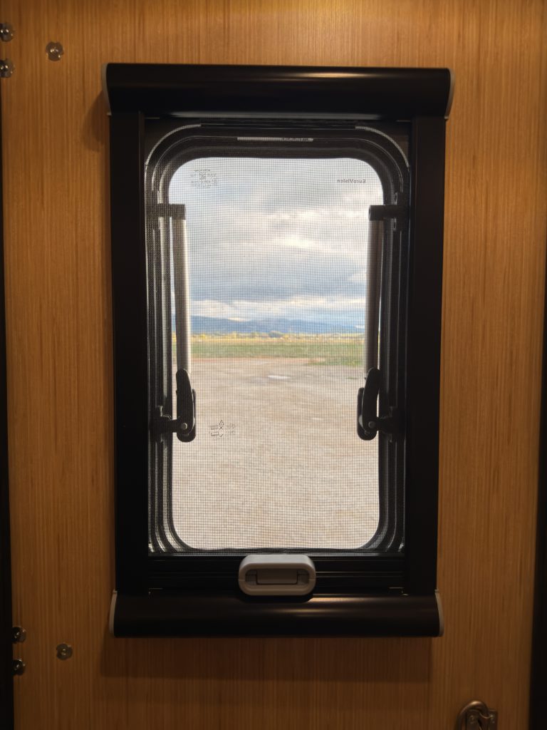 Van Niewkoop Camp #136: Black-framed window in the wood Dutch entry door.