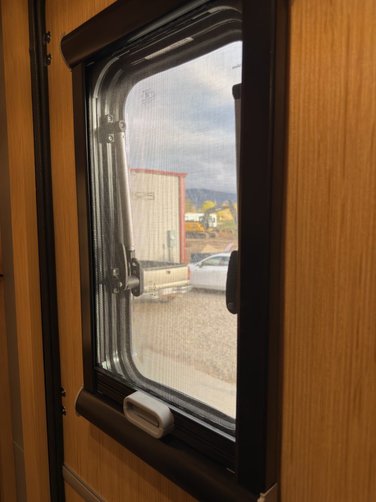 Van Niewkoop Camp #136: Angled close view of the Dutch entry-door window and its frame.