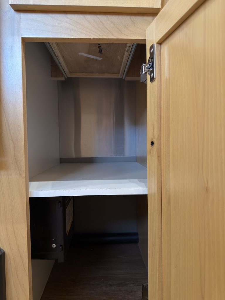 Open base cabinet showing an interior shelf in Van Niewkoop Camp #136.