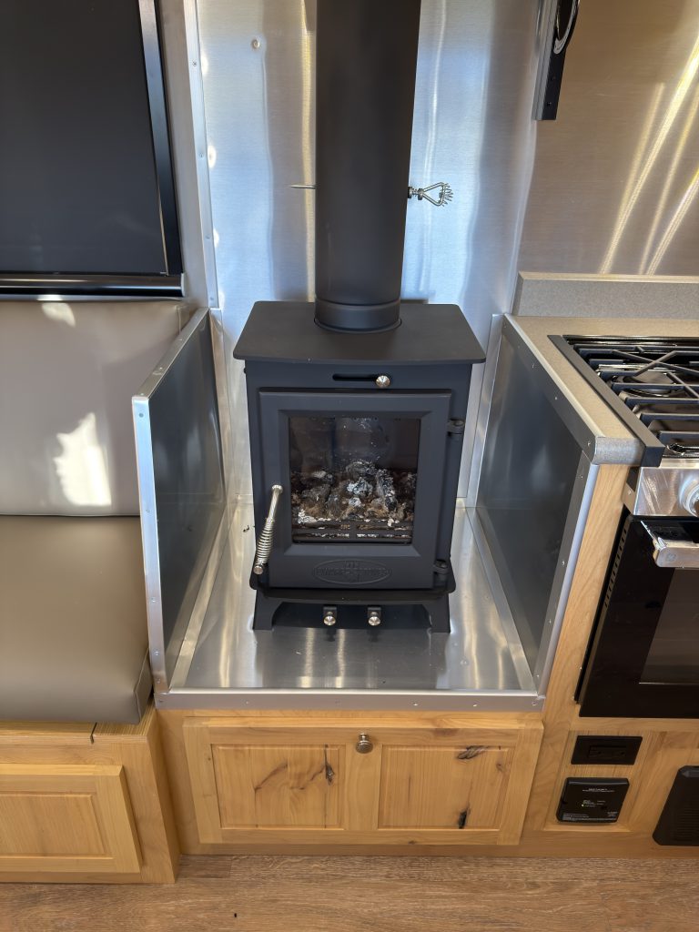 Van Niewkoop Camp #136: Compact wood-burning stove in a fire-protected, metal-lined alcove beside the kitchen range.