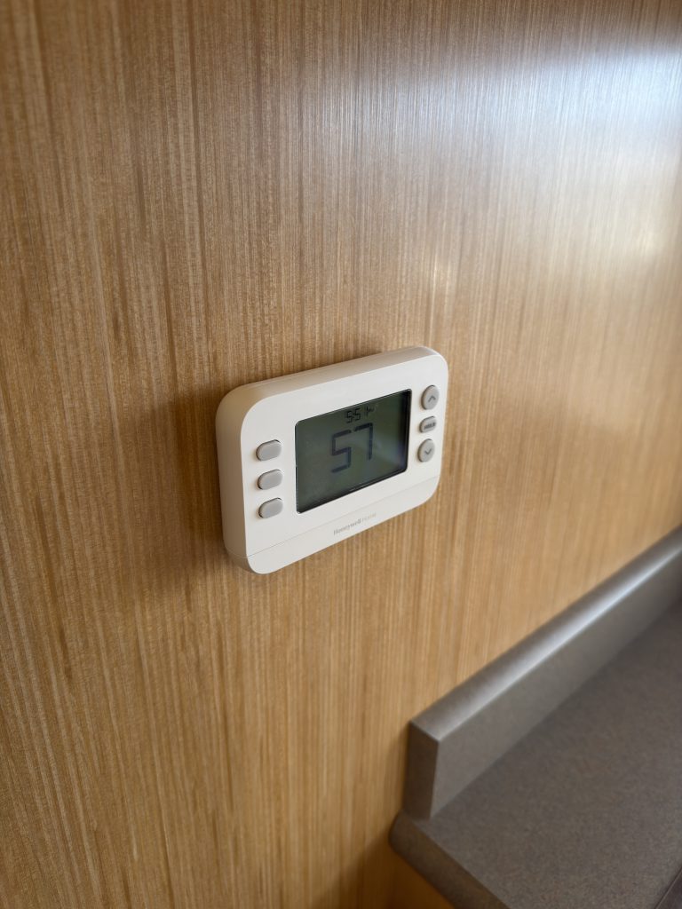 Small thermostat mounted on the wood interior wall in Van Niewkoop Camp #136.