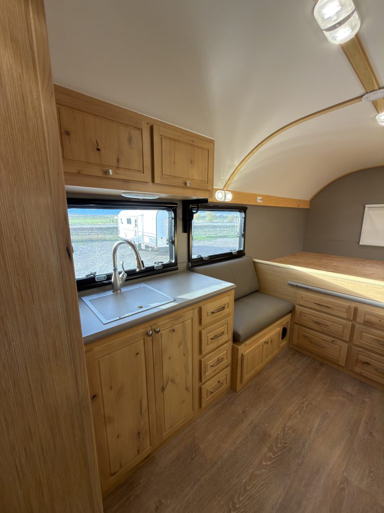 Van Niewkoop Camp #136: Kitchen counter and hardwood cabinetry beside the raised California king bed platform.