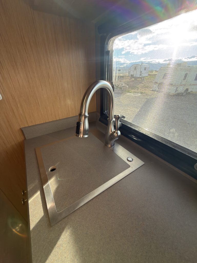 Van Niewkoop Camp #136: Kitchen sink with its countertop cut-out set into the basin beside the faucet and backsplash.