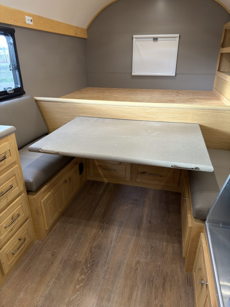 Van Niewkoop Camp #136: Four-person dinette with its pull-out table extended between the bench seats beneath the raised bed.
