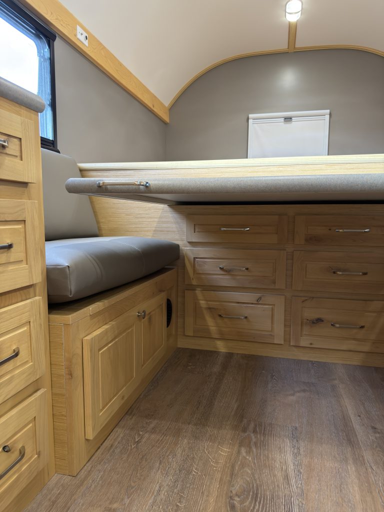 Van Niewkoop Camp #136: View beneath the extended dinette table toward the drawers below the raised bed.
