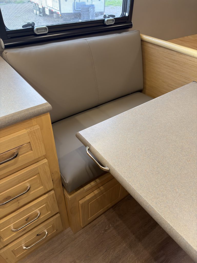 Van Niewkoop Camp #136: Upholstered dinette bench beneath the side window beside the pull-out table.