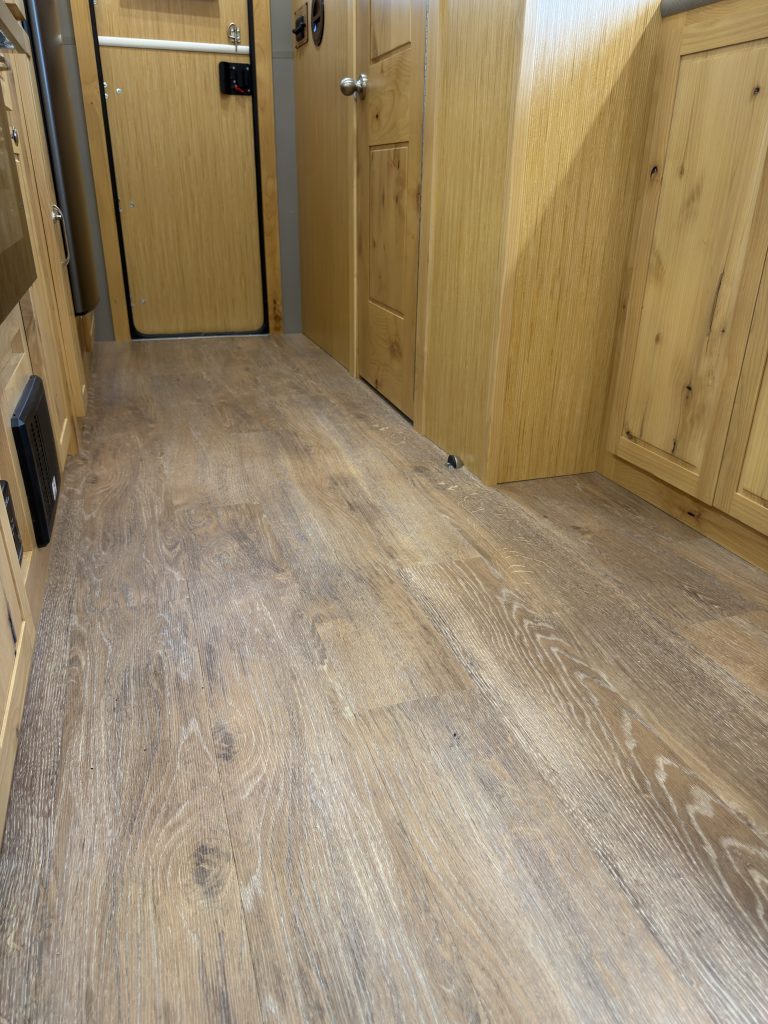 Van Niewkoop Camp #136: Low view of the Karndean Honey Oak luxury vinyl plank flooring and lower wood cabinetry.