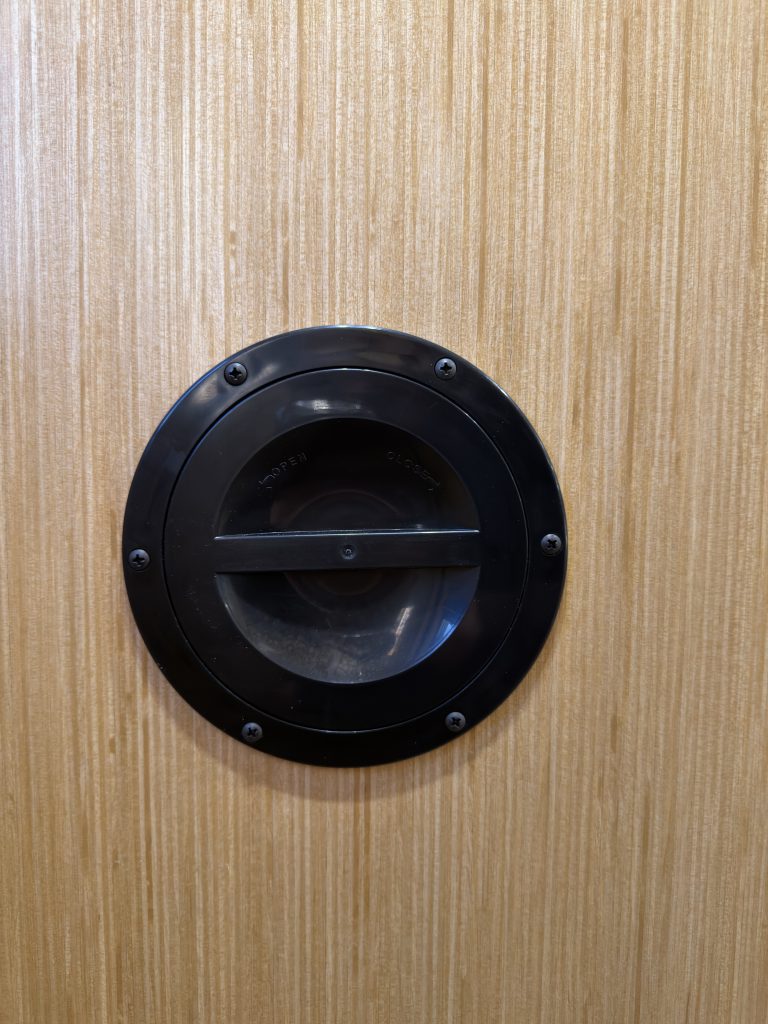 Round access cover closed on the interior wood panel in Van Niewkoop Camp #136.