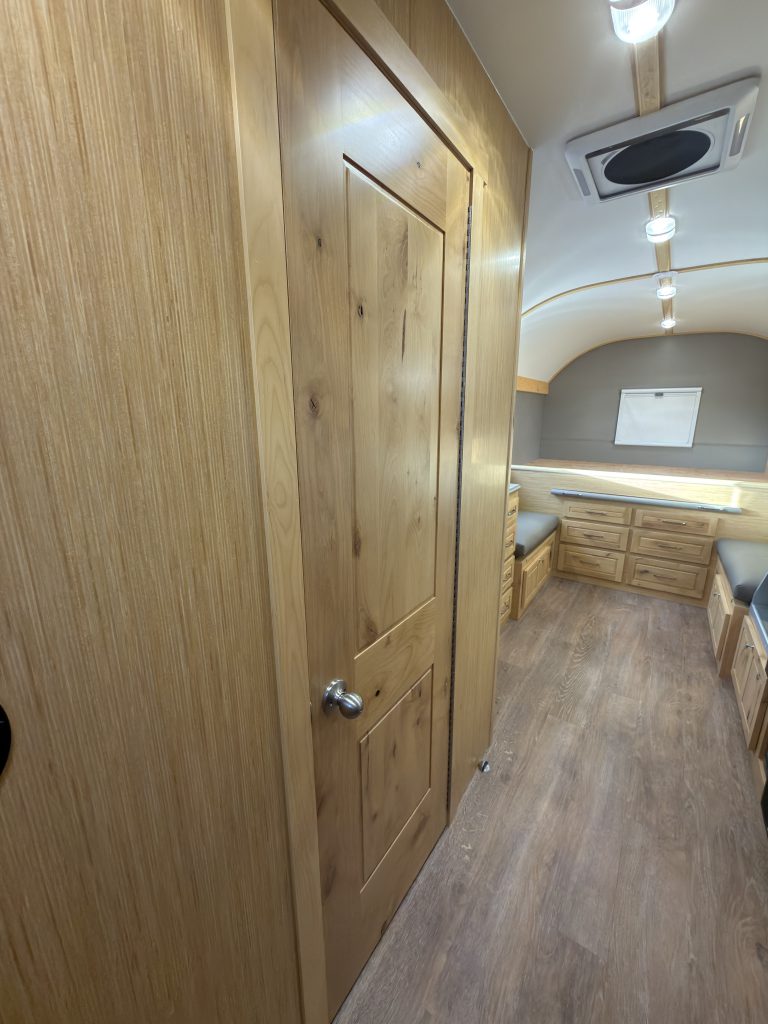 Interior aisle beside the bathroom door toward the rear platform in Van Niewkoop Camp #136.