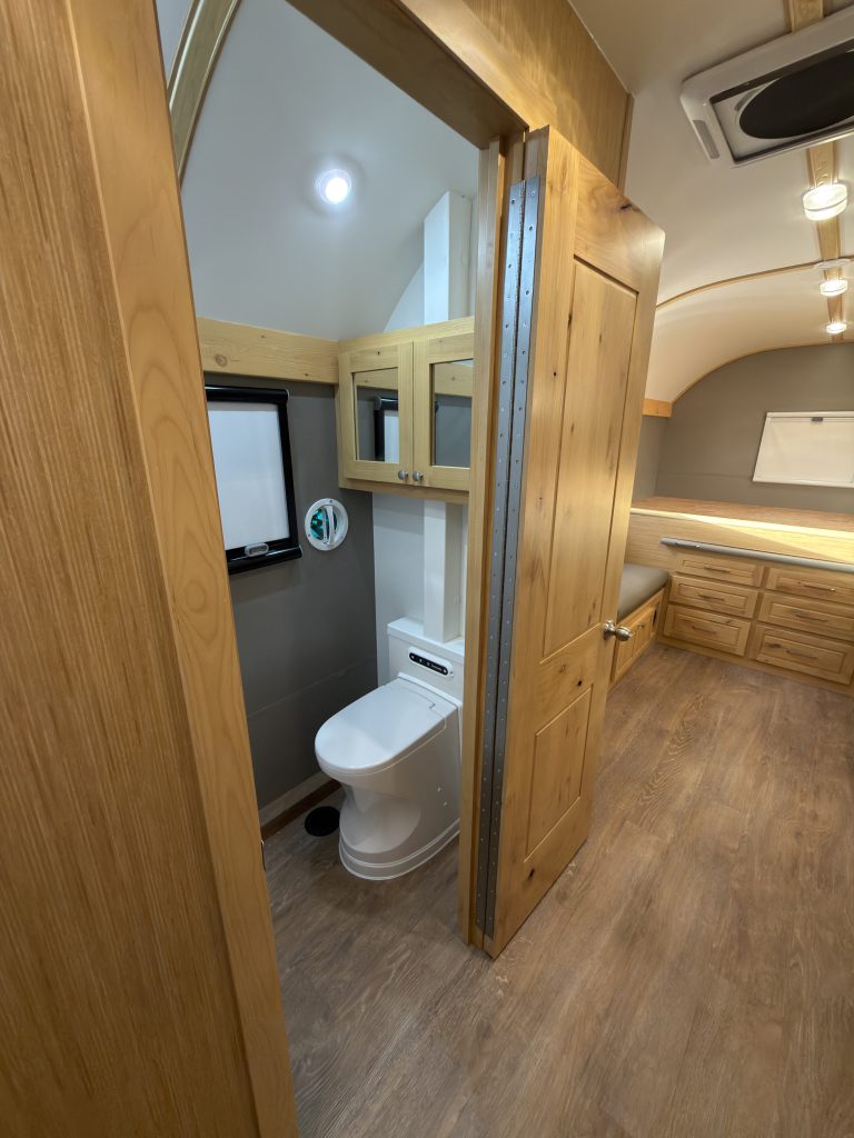 Van Niewkoop Camp #136: Open bathroom doorway showing the Cinderella incinerating toilet beside the kitchen aisle.