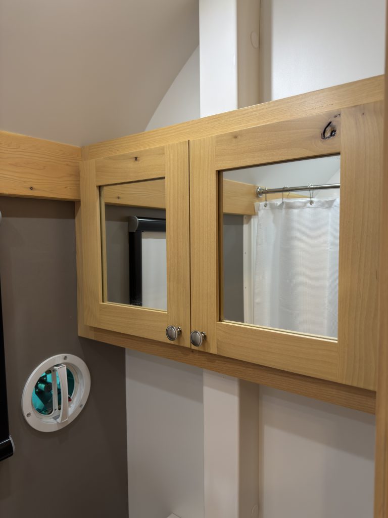 Van Niewkoop Camp #136: Wood-framed mirrored medicine cabinet mounted above the Cinderella toilet.