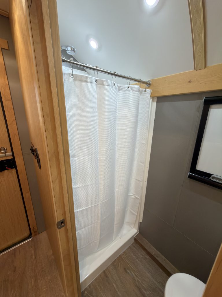 Van Niewkoop Camp #136: Bathroom shower enclosure with its curtain closed.