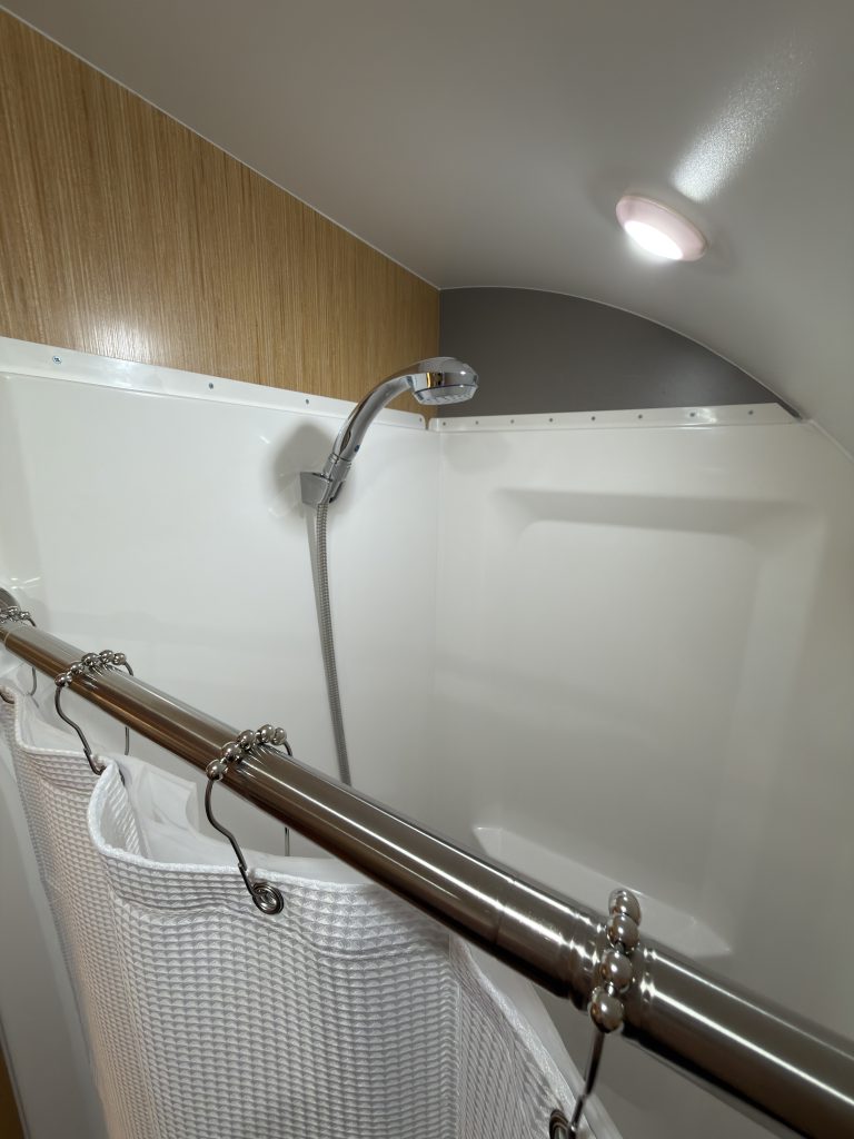 Van Niewkoop Camp #136: Shower head, flexible hose, and stainless steel fixtures inside the shower enclosure.