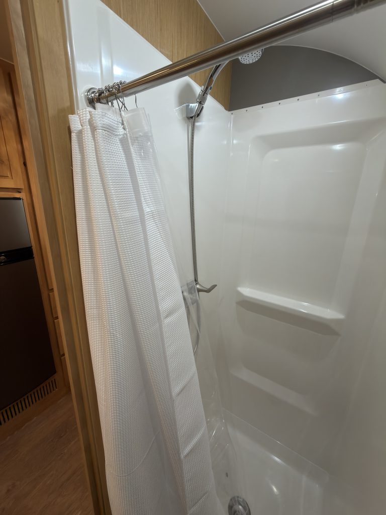 Van Niewkoop Camp #136: Molded shower wall with integrated shelving beside the shower hose.