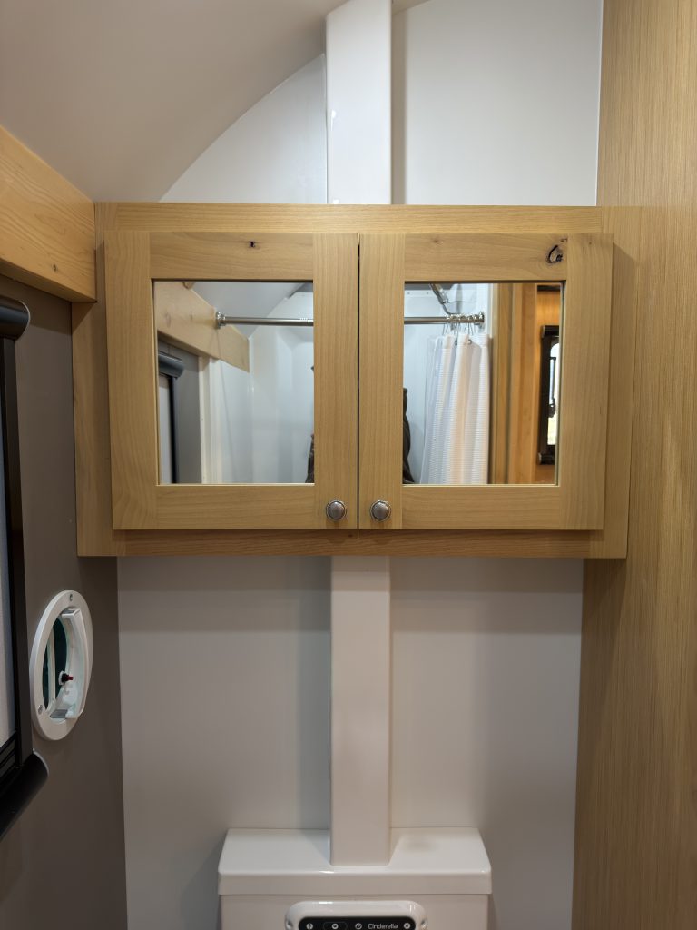 Van Niewkoop Camp #136: Mirrored medicine cabinet and wood wall trim above the Cinderella toilet.