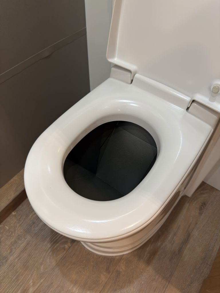 Van Niewkoop Camp #136: Cinderella incinerating travel toilet with its lid raised.