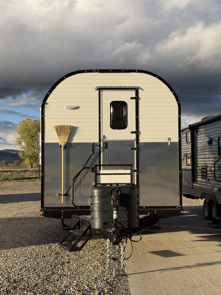 Van Niewkoop Camp #136: Straight front view showing the Dutch door, corn broom, propane tank cover, and trailer hitch.
