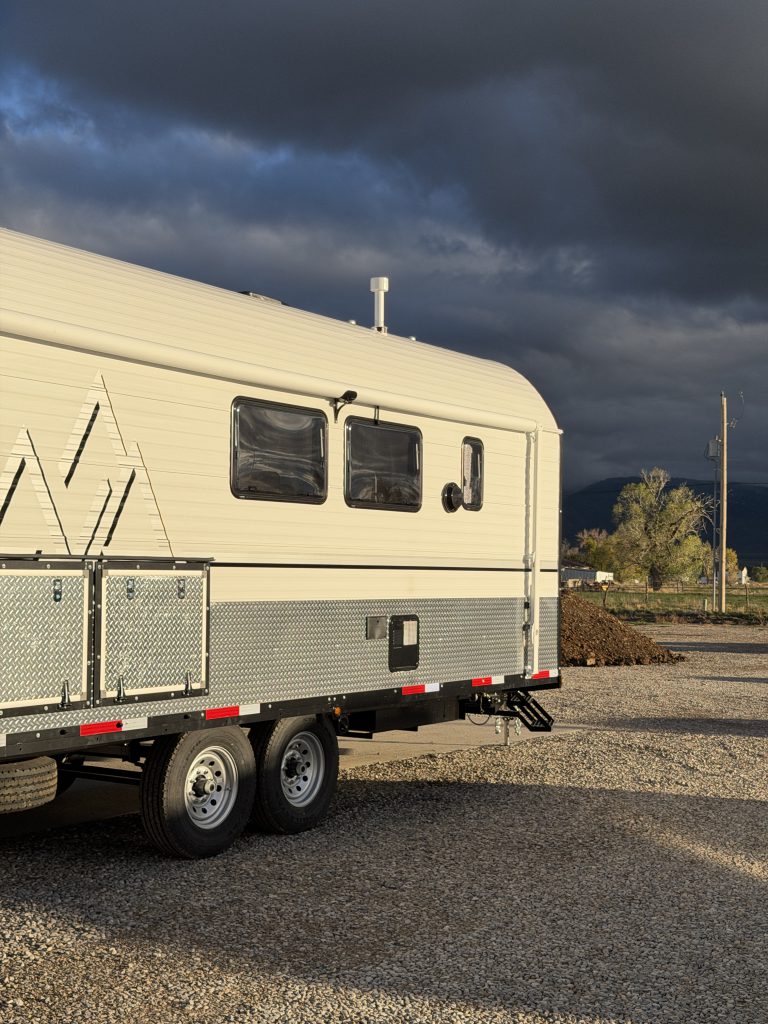 Side wall, windows, and tandem wheels near the rear corner in Van Niewkoop Camp #136.