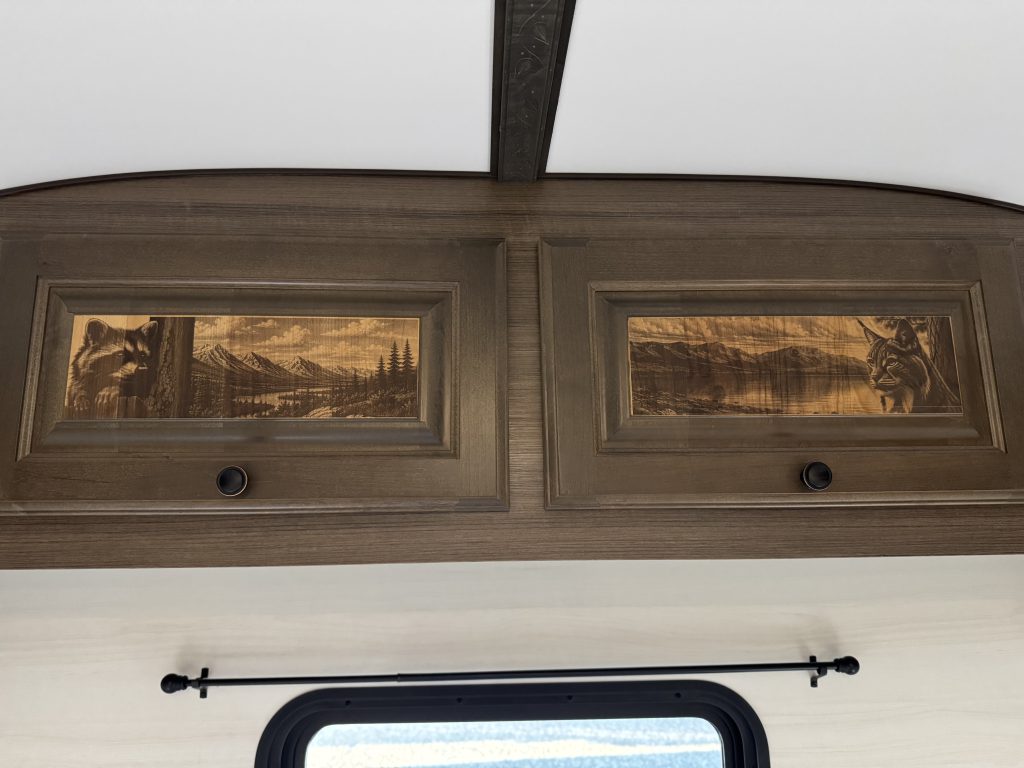 Overhead wood cabinet doors with scenic panel inserts above a window in Watson Camp #134.