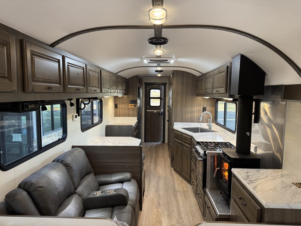 View down the interior showing seating, kitchen cabinetry, television, and entry door in Watson Camp #134.