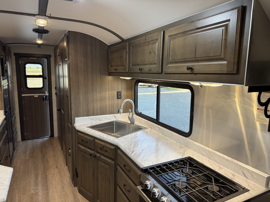 Kitchen countertop, sink, range, and overhead cabinets beside the entry area in Watson Camp #134.
