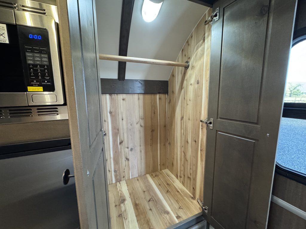 Large entryway closet with a wood-lined interior, hanging rail, and overhead light in Watson Camp #134.