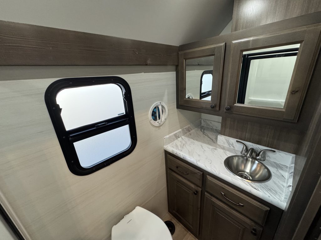Bathroom vanity with a round metal sink, mirrored cabinets, and a window in Watson Camp #134.