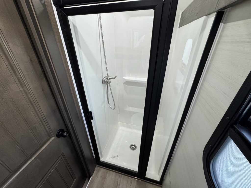 Shower enclosure with a black-framed glass door and handheld shower fixture in Watson Camp #134.