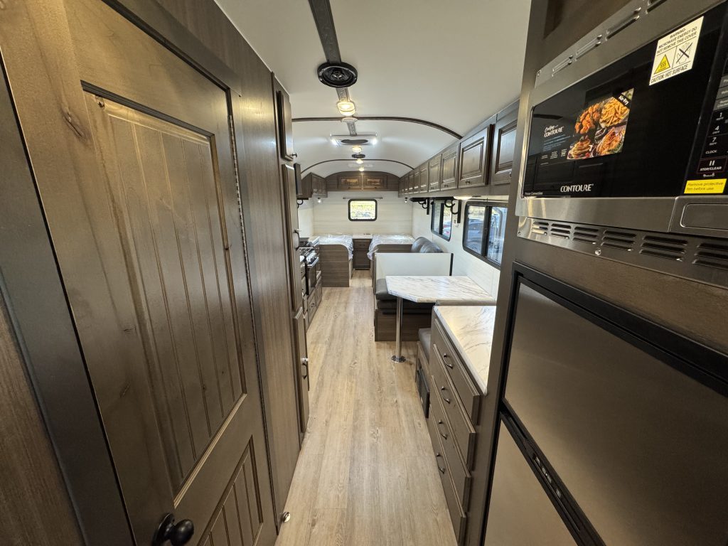 Interior aisle beside the microwave and refrigerator, looking toward tables and seating in Watson Camp #134.