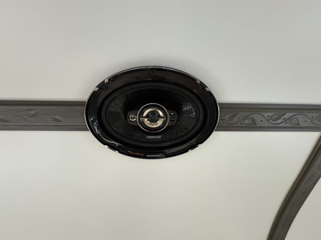 Round black speaker mounted along the rosewood ceiling trim in Watson Camp #134.